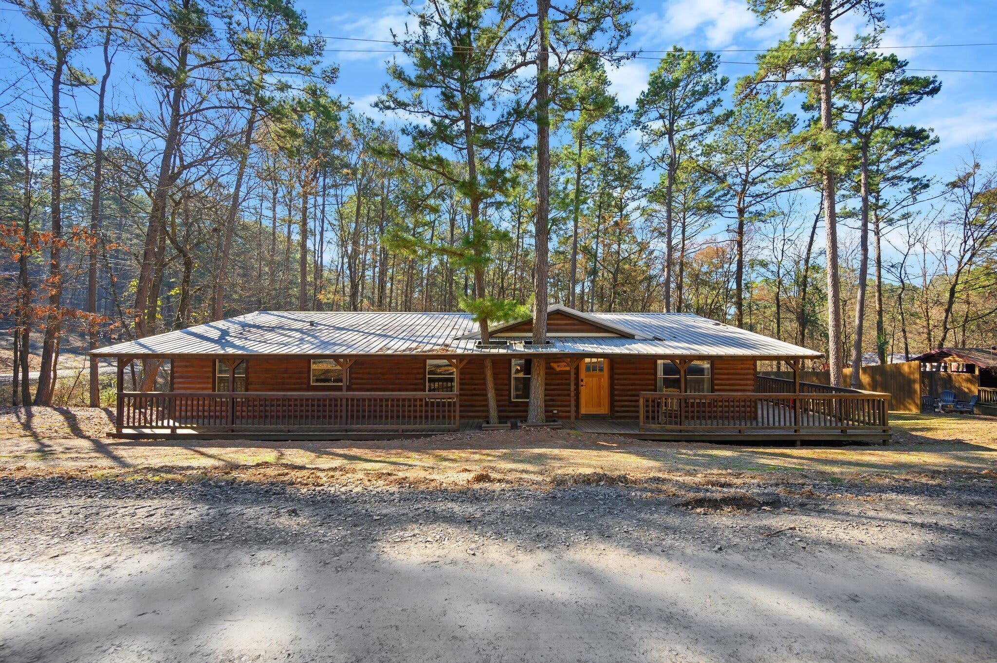 A rustic cabin with a metal roof, wooden deck, and a porch.