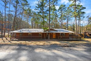 A rustic cabin with a metal roof, wooden deck, and a porch. - Outlaw Rose Cabin for 8! (Broken Bow)