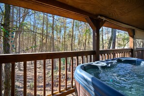 A hot tub on a wooden deck with a view of a forest. - Outlaw Rose Cabin for 8! (Broken Bow)