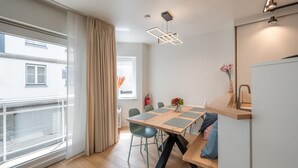 A modern kitchen with a wooden table, chairs, and pendant lights. - Apt by Duinbergen Beach (Knokke-Heist)