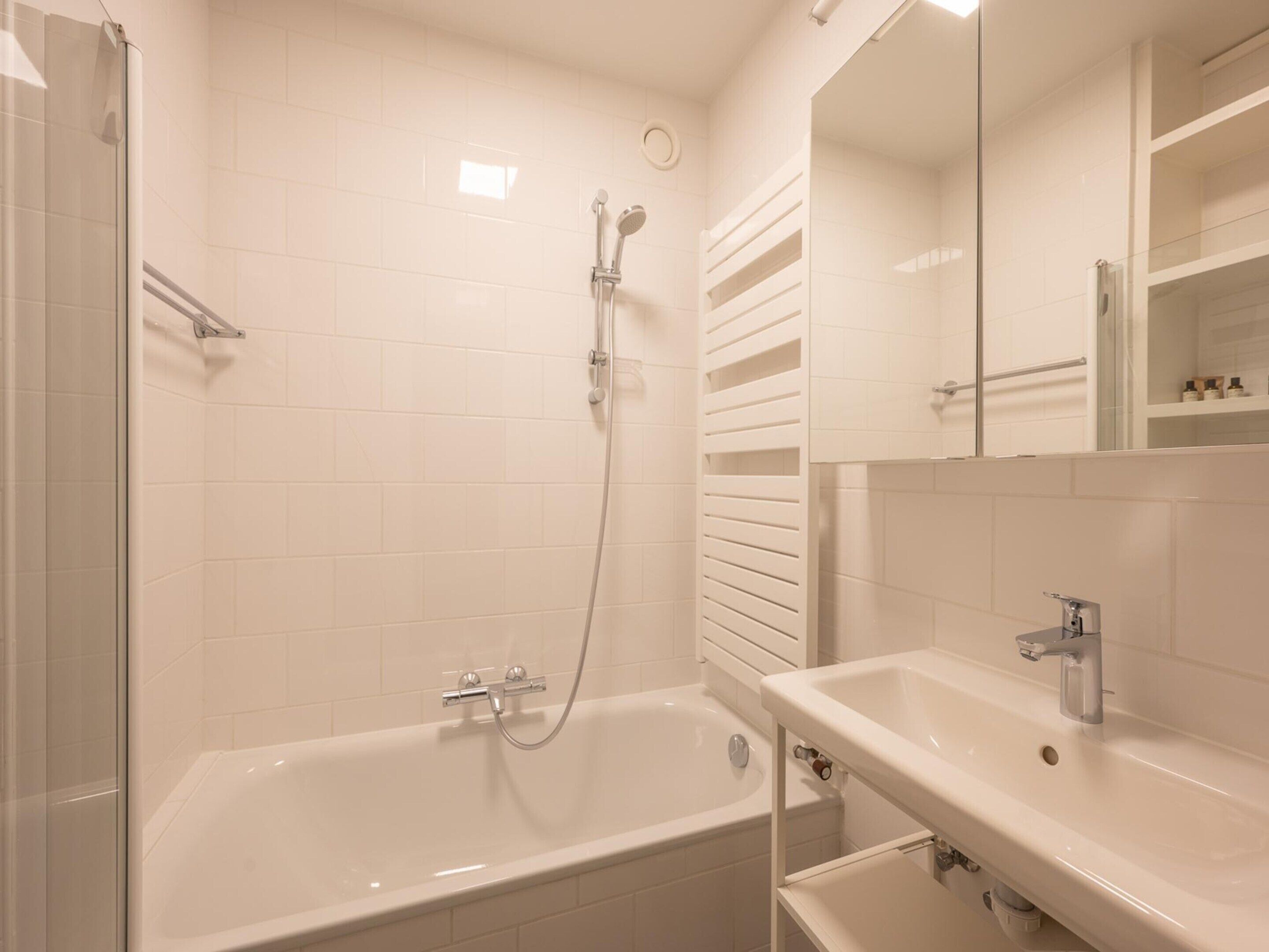 A modern bathroom with a bathtub, a shower, and a sink.