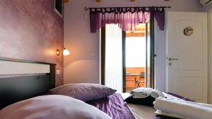 Une chambre à coucher avec un lit, des oreillers, une table de chevet, une lampe et une vue sur un espace extérieur.