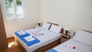 A hotel room with two beds, each with a blue towel and a white towel, and a window with a view of trees. - Charming Seaside Escape in Kotor (Donji Stoliv)