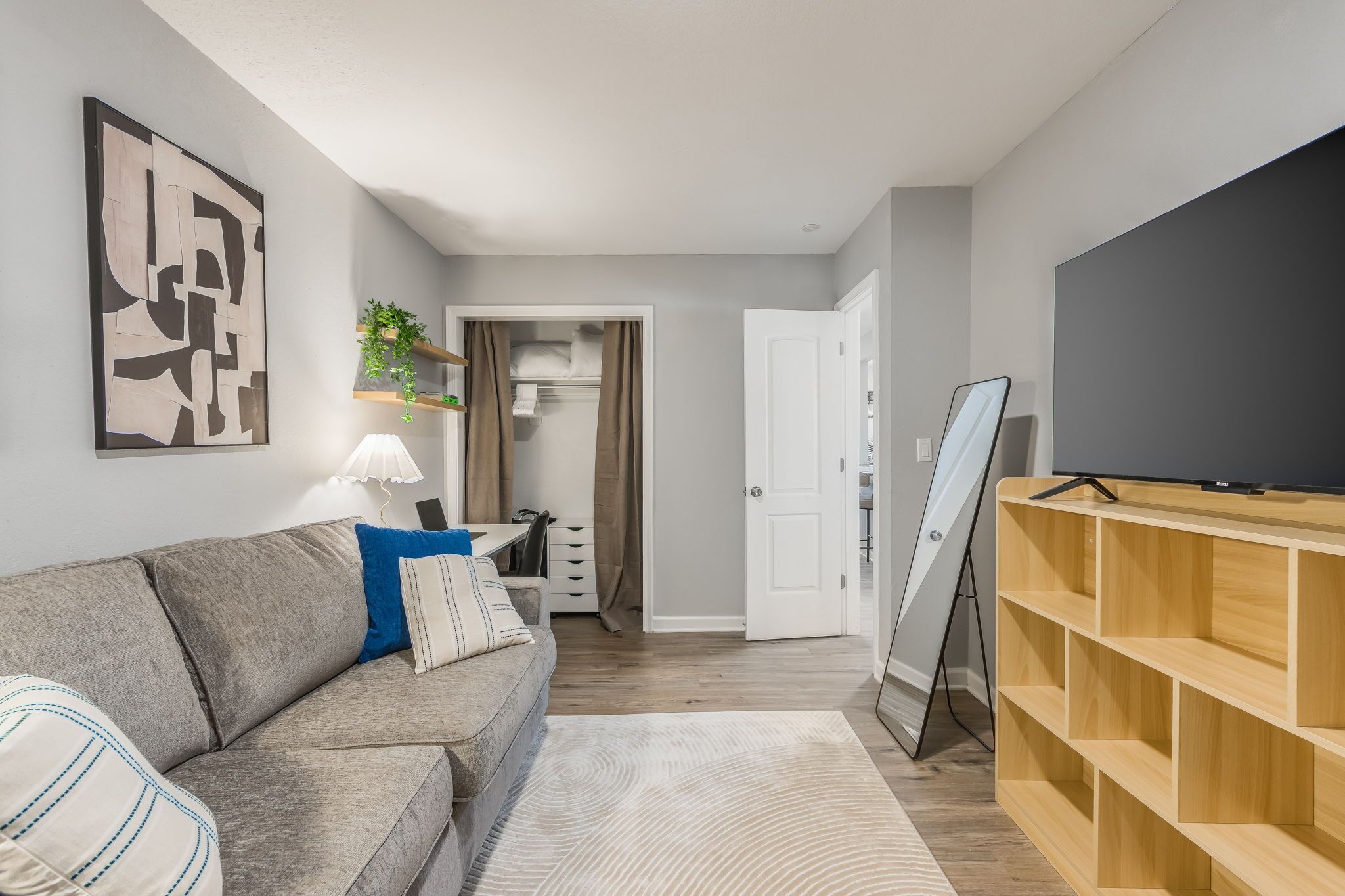 Un salon moderne avec un canapé gris, un meuble pour la télévision et une étagère en bois.