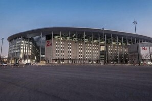 A large, modern stadium with a curved roof and multiple levels of seating. - Minhua Business Hostel (Shanghai)