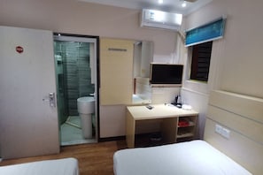 A hotel room with a bed, a desk, a television, and a bathroom visible through a glass door. - Minhua Business Hostel (Shanghai)