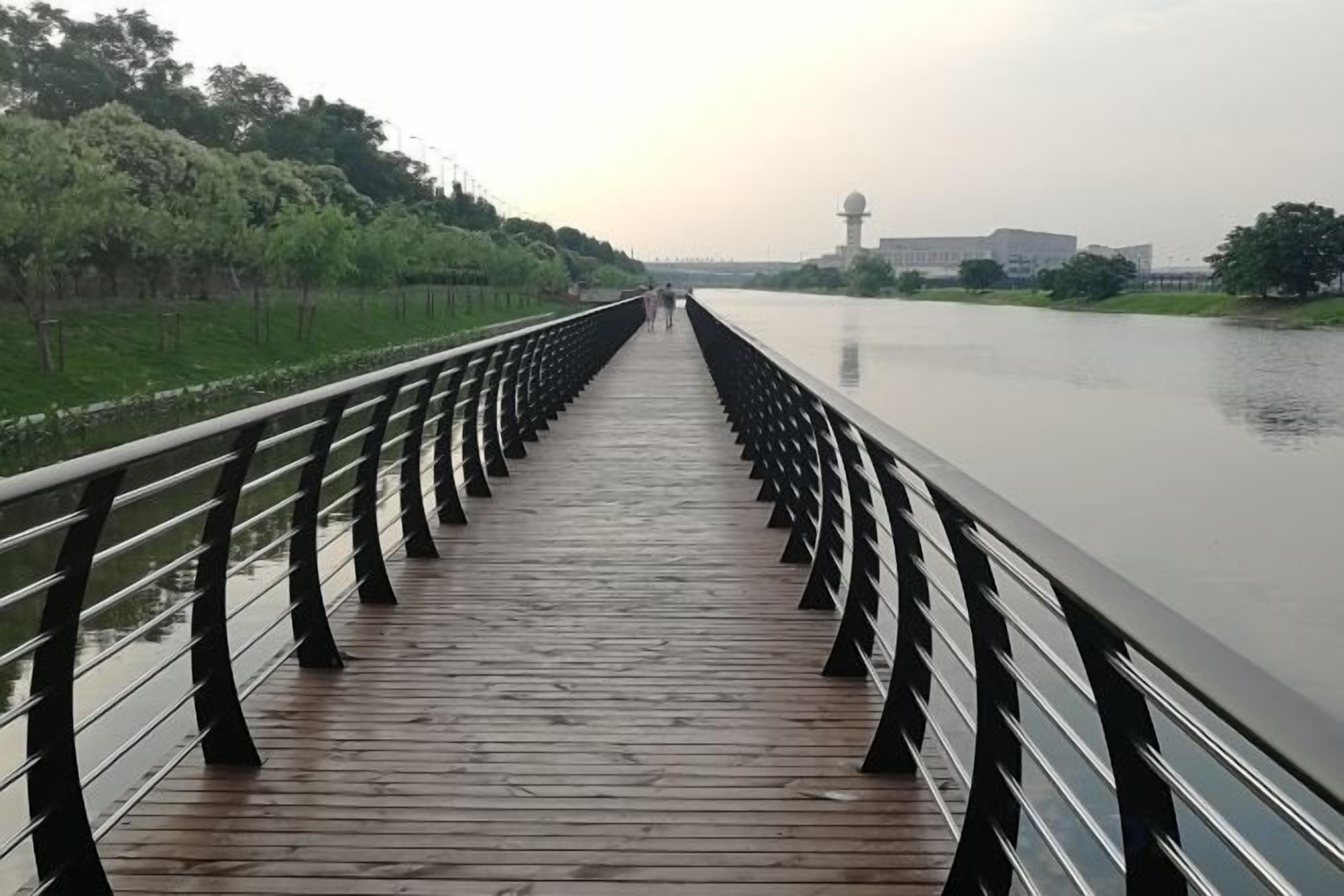 A wooden bridge with railings extending over a calm body of water.
