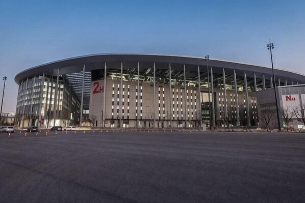 A large, modern stadium with a curved roof and multiple levels of seating.