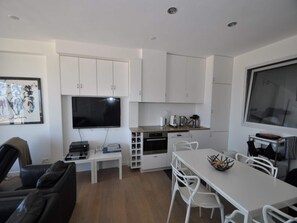 A compact living space with a kitchenette, a dining area, and a seating area with a TV mounted on the wall. - Sea Views in Heart of Zoute (Knokke-Heist)