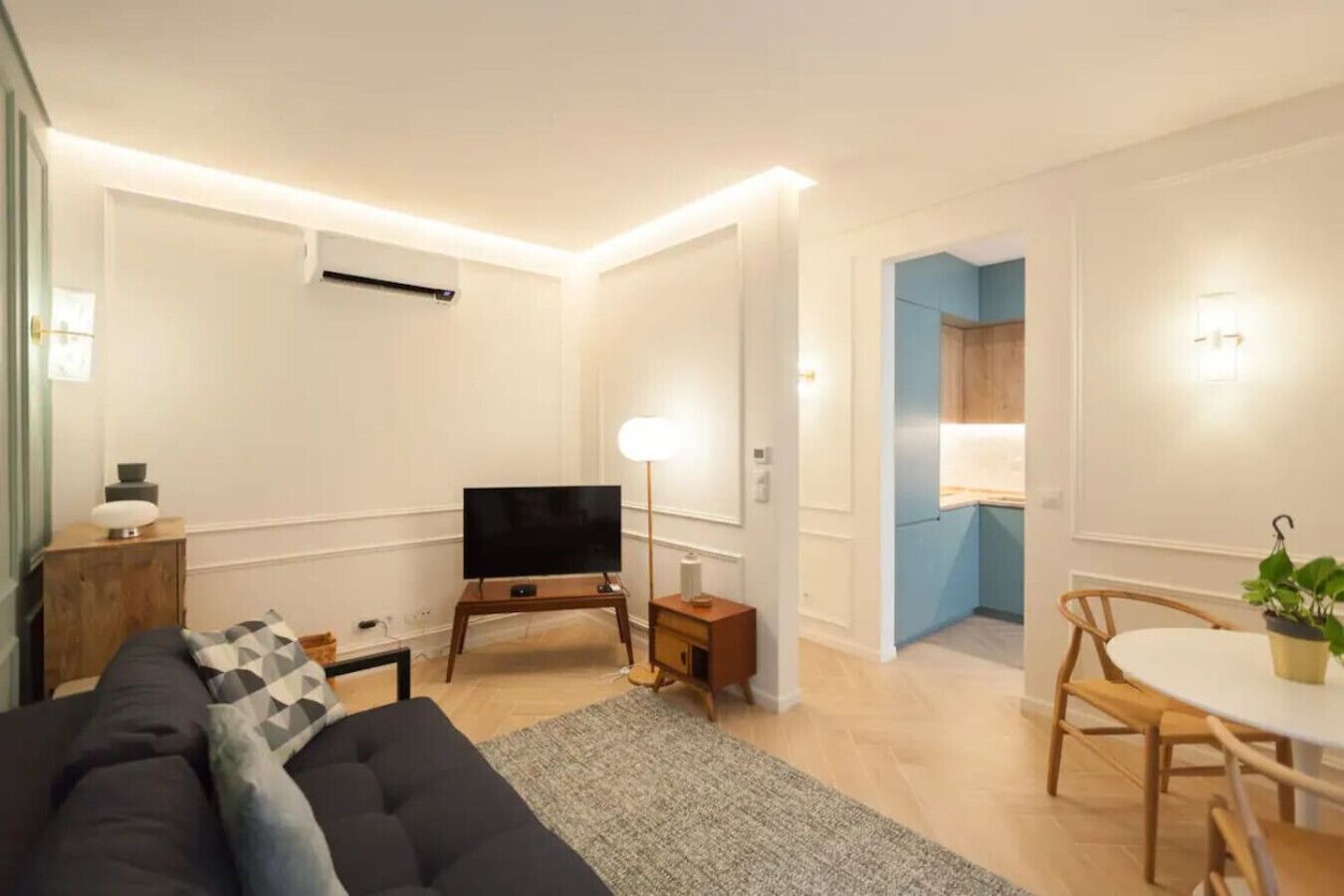 Ein modernes Wohnzimmer mit Sofa, Fernseher und Essbereich mit Tisch und Stühlen.