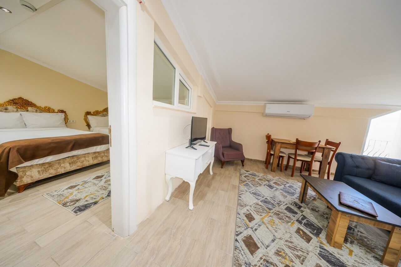 Un dormitorio con cama, escritorio, silla, sofá y una zona de comedor con sillas y mesa.