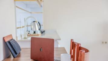 Um laptop sobre uma mesa de madeira, com uma caneca branca e uma cadeira.