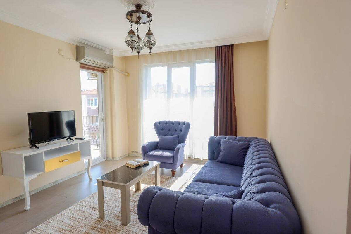 Ein Wohnzimmer mit Sofa, Sessel, Fernseher und Deckenventilator.