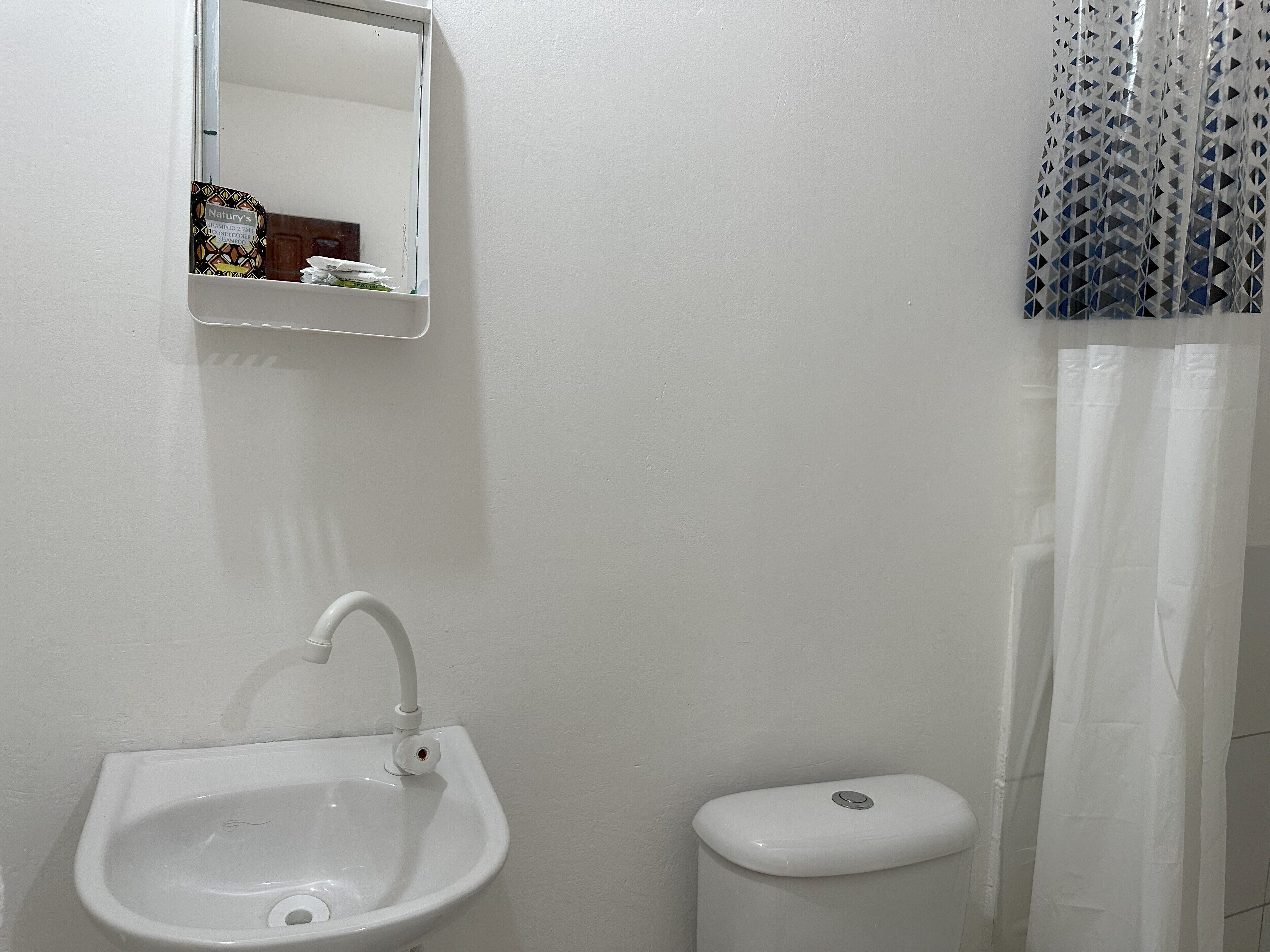 A bathroom with a white sink, a toilet, and a mirror.