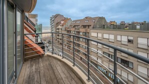 A balcony with a view of a coastal cityscape, featuring multi-story buildings and a beach in the background. - Duplex in Knokke-heist Near the Beach (Knokke-Heist)
