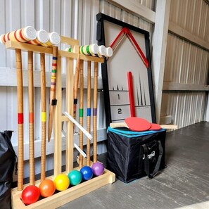 A ping pong table with balls and paddles, a bag, and a wall-mounted target.