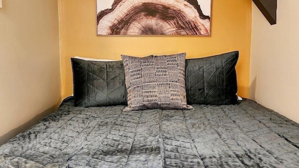 A bedroom with a bed, two pillows, and a painting on the wall.