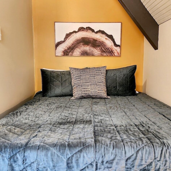 Un dormitorio con una cama, dos almohadas y un cuadro en la pared.