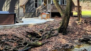A cabin with a wooden deck, a staircase leading to a porch, and a small outdoor seating area.