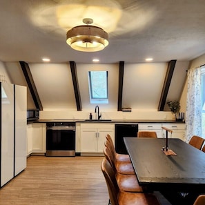 A modern kitchen with a central island, built-in appliances, and a dining area with a table and chairs. - RockFall Retreat! Nature's Haven (Lancaster)