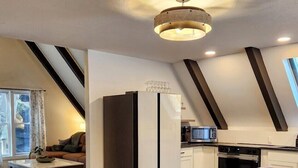 A modern kitchen with a dining area, featuring a large table and chairs, a refrigerator, and a microwave.