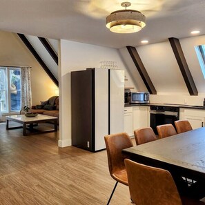 Una cocina moderna con comedor, que incluye una mesa grande, sillas, un refrigerador y un microondas.