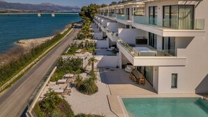 A modern hotel with a pool, balconies, and a view of the sea.