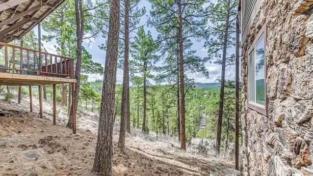 A rustic cabin with a wooden deck overlooking a forested area. - Half-Mi to Midtown: Family Retreat w/ Mtn Views! (Ruidoso)