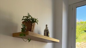 A kitchen with a white sink, a gold faucet, a microwave, and a shelf with a plant and a bottle. - Village house in the countryside, T3 duplex with master suite. (Ville-sous-Anjou)