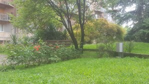 A lush garden with a wooden bench, dense greenery, and a building in the background. - MILAN NAVIGLI LARGE APARTMENT VIA SAVONA-TORTONA (Milano)