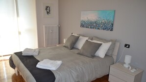 A neatly made bed with pillows and a blanket, a bedside table with a lamp, and a painting on the wall. - MILAN NAVIGLI LARGE APARTMENT VIA SAVONA-TORTONA (Milano)