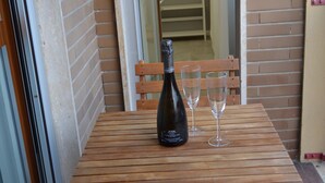 A wooden table with a bottle and two glasses, set against a brick wall. - MILAN NAVIGLI LARGE APARTMENT VIA SAVONA-TORTONA (Milano)