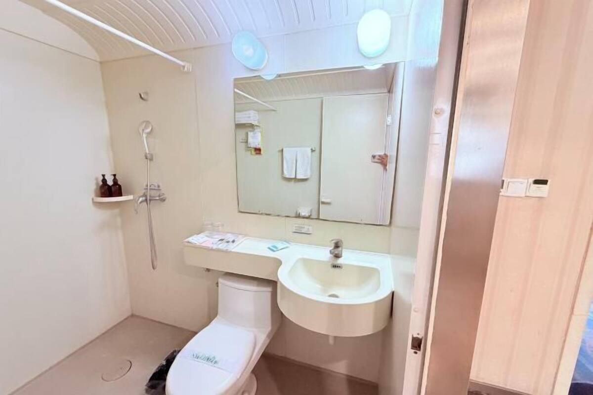 A small, clean bathroom with a toilet, sink, and shower.