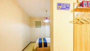 A hotel room with a bed, a hanging light fixture, a wooden wardrobe, and a wall-mounted sign. - Yumeida Boutique Hotel Xinxiang Changheng (Changyuan)