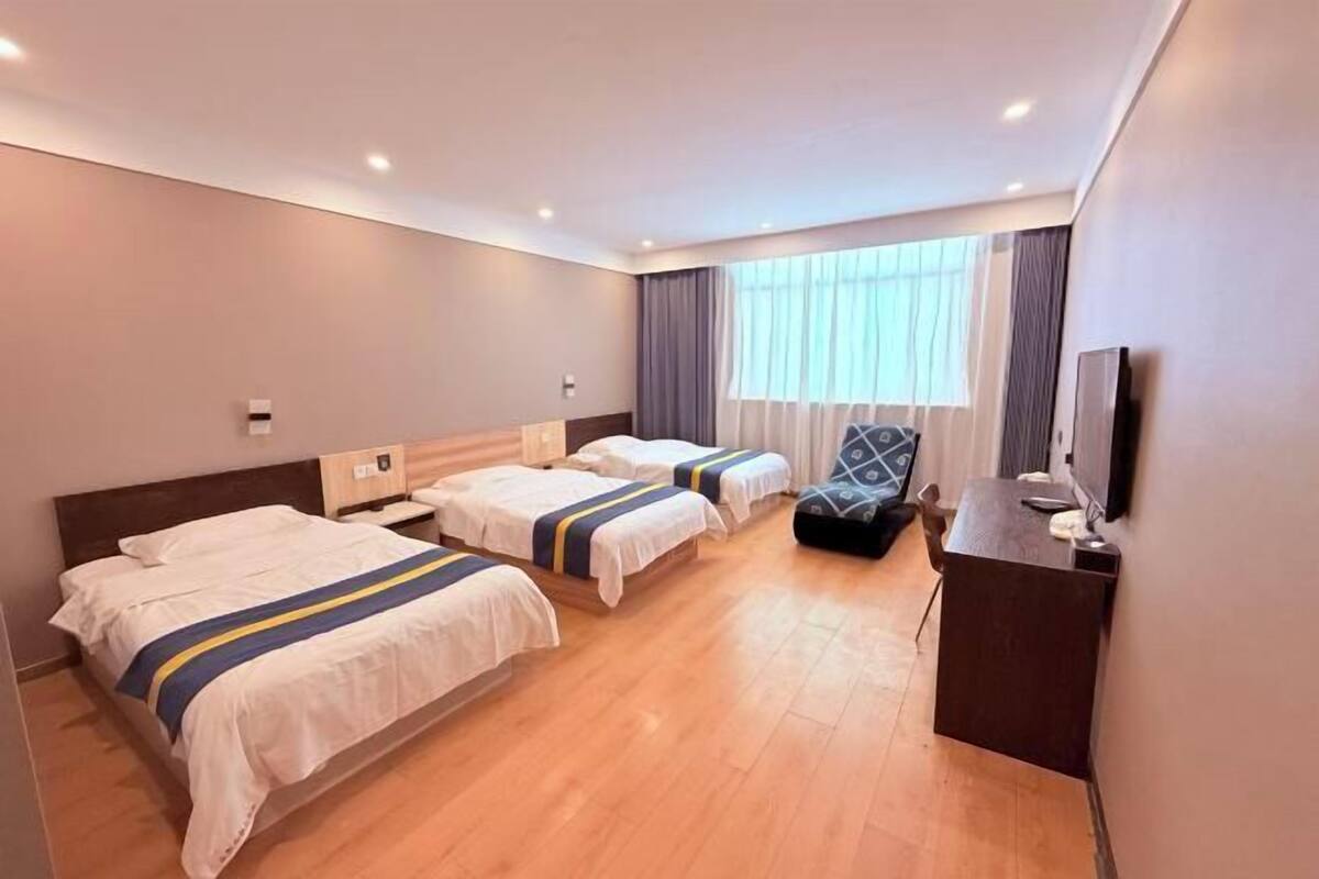 Ein Hotelzimmer mit zwei Betten, einem Schreibtisch, einem Stuhl und einem Fernseher.