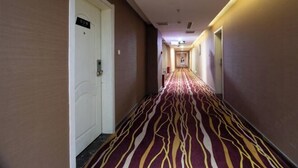 A hotel corridor with a patterned carpet, white doors, and a sign on the wall. - Yumeida Boutique Hotel Xinxiang Changheng (Changyuan)