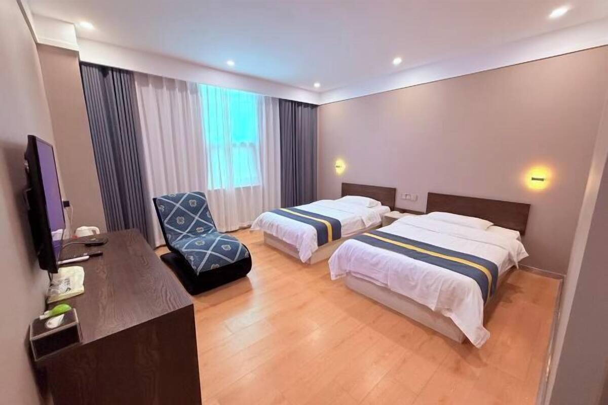 Ein Hotelzimmer mit zwei Betten, einem Schreibtisch, einem Stuhl und einem Fernseher.