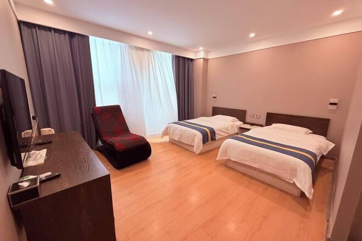Ein Hotelzimmer mit zwei Betten, einem Schreibtisch, einem Stuhl und einem Fernseher.