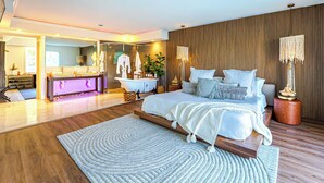 Un dormitorio moderno con una cama grande, un baño con bañera y piso de madera.