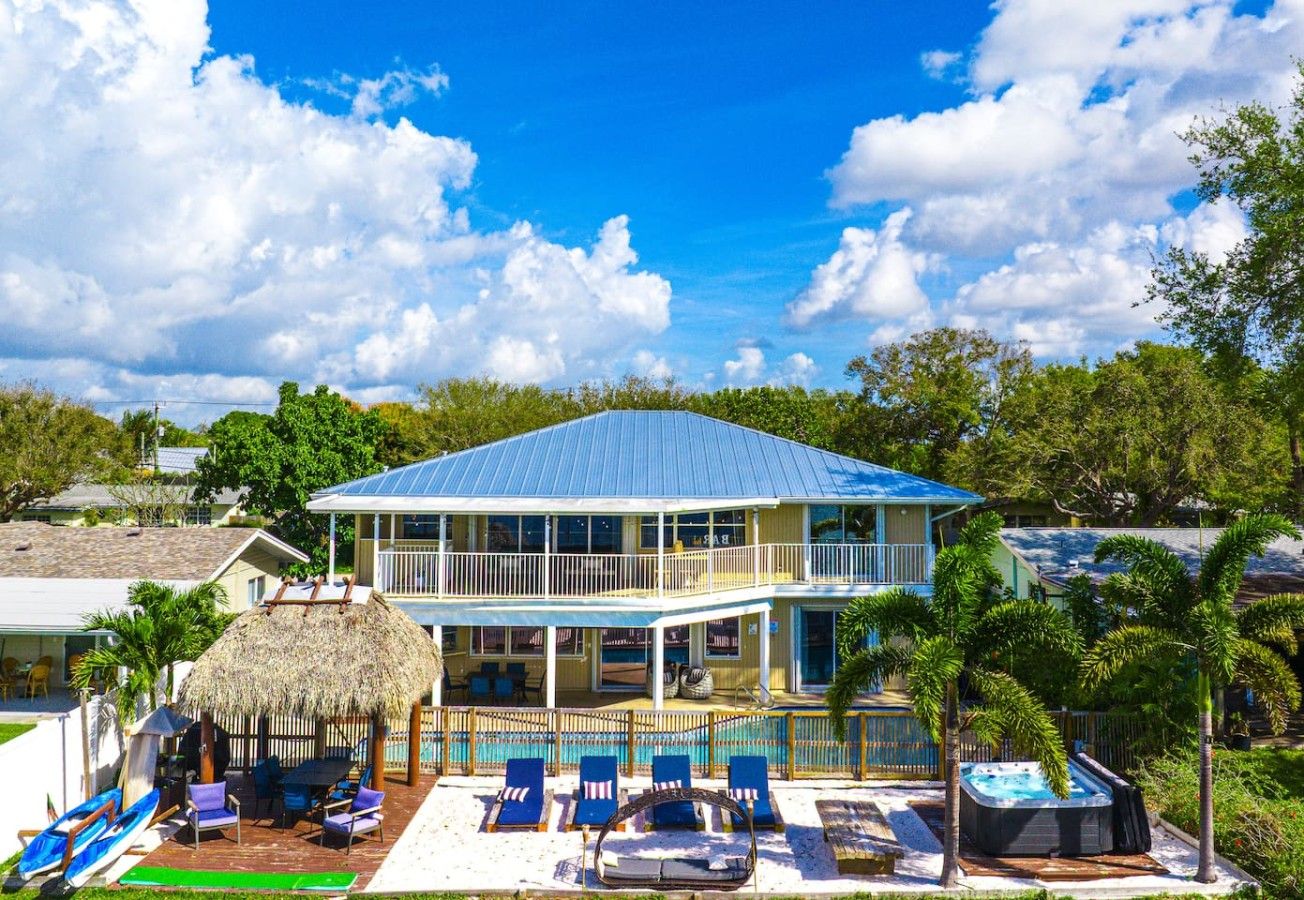 Una casa de dos pisos con piscina, sillas de descanso y jacuzzi.