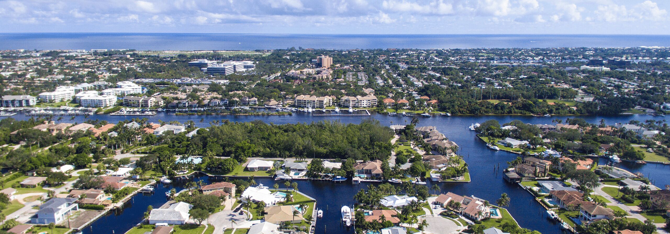 Una zona residencial costera con casas, un puerto deportivo y una extensa masa de agua.