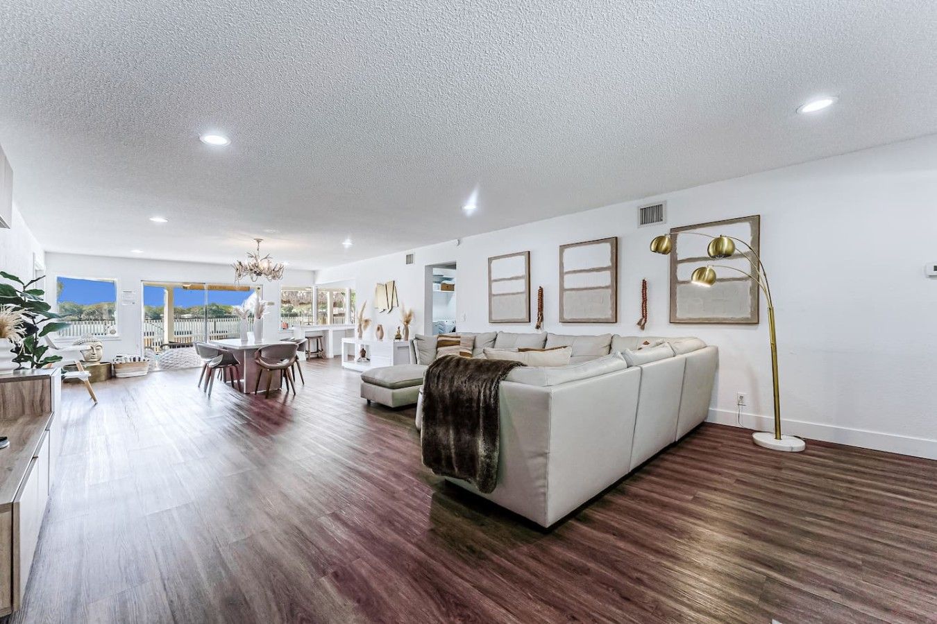 A spacious living area with a large sofa, a dining table, and a kitchen in the background.