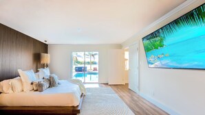 Un dormitorio con cama, vista a una piscina y un ventanal grande.