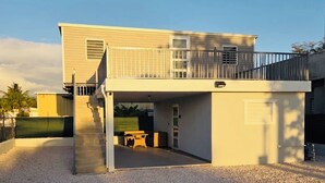 A two-story house with a covered patio area and a staircase leading to the upper level.