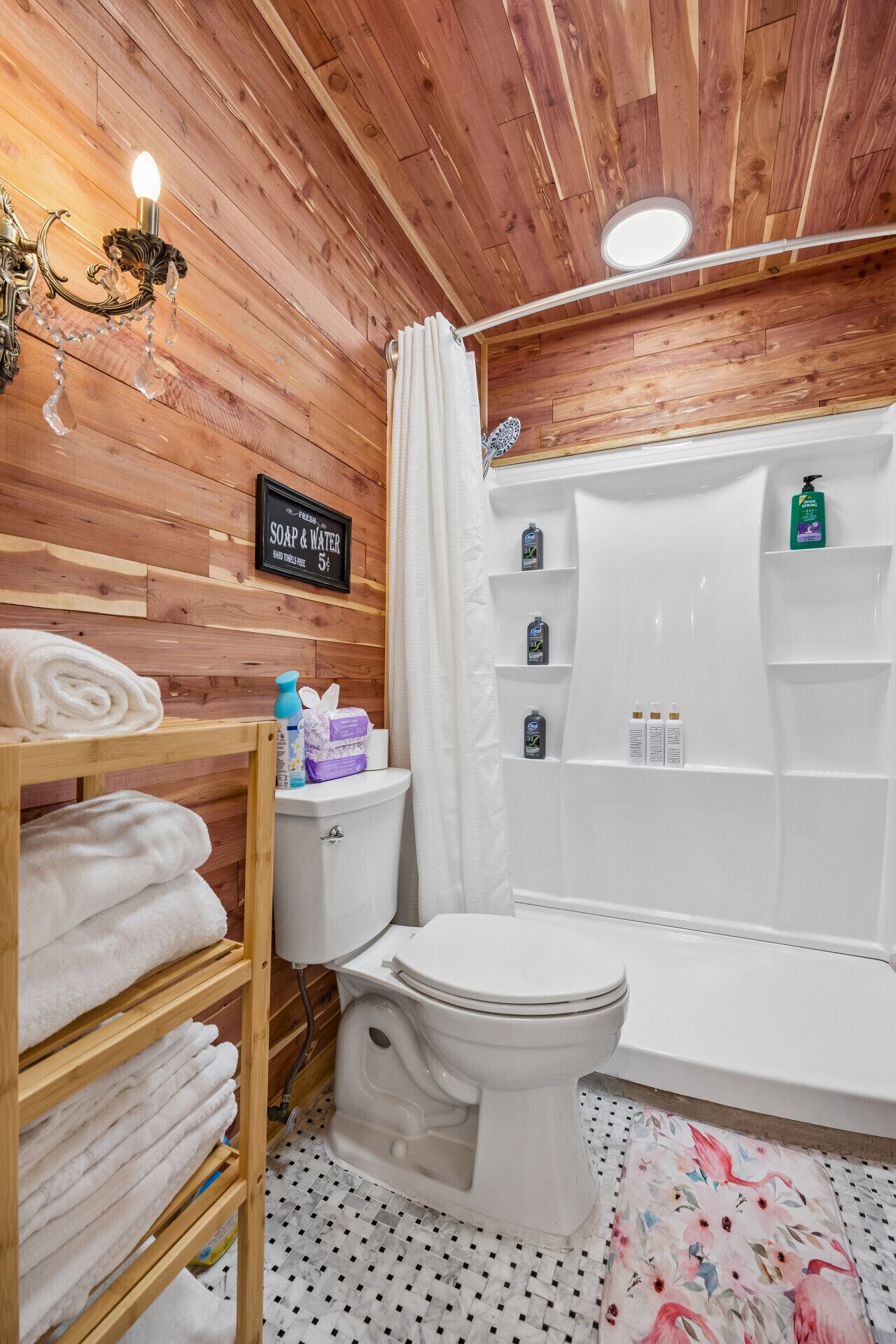 Un baño con paneles de madera, un inodoro, una ducha y un estante con artículos de aseo.