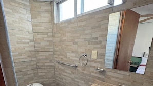 Une salle de bain comprenant des toilettes, un lavabo et un espace douche.