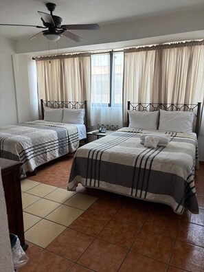 A hotel room with two beds, a ceiling fan, a nightstand with a phone, and a window with curtains. - Hotel San Agustin (Queretaro)