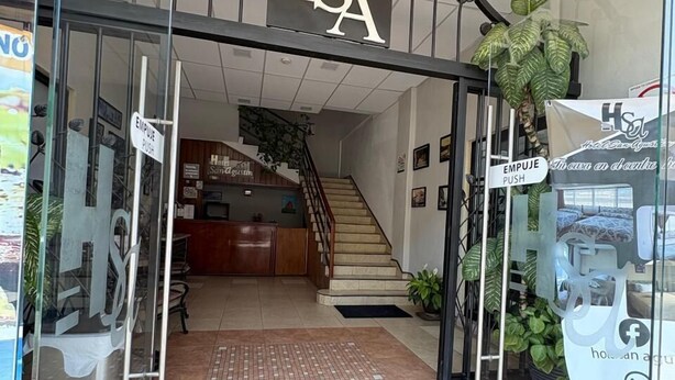 L’entrée d’un hôtel, avec une porte en verre, un escalier menant à l’intérieur et un comptoir d’accueil.