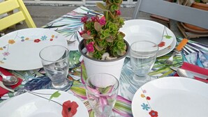 A table set for dining with plates, cutlery, glasses, and a potted plant.