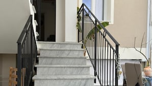 A staircase with marble steps and black railings leading to an upper floor.